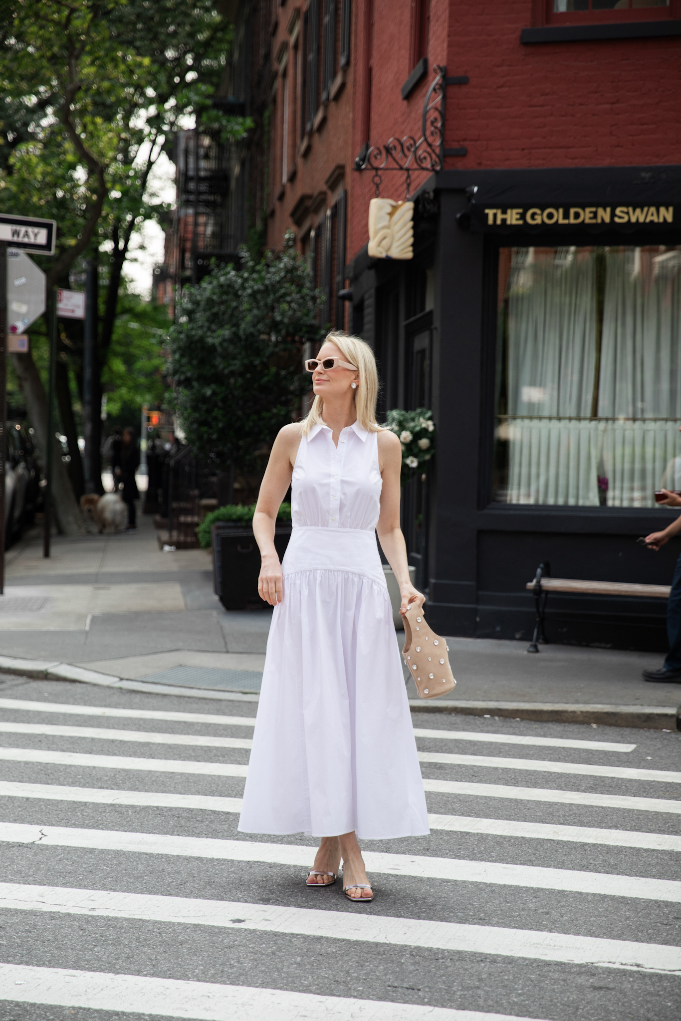 MERRITT BECK IN A STAUD ROMY SLEEVELESS SHIRTDRESS AND A KHAITE LIVIA BAG IN POWDER SUEDE FOR A A SOPHISTICATED SUMMER FROCK