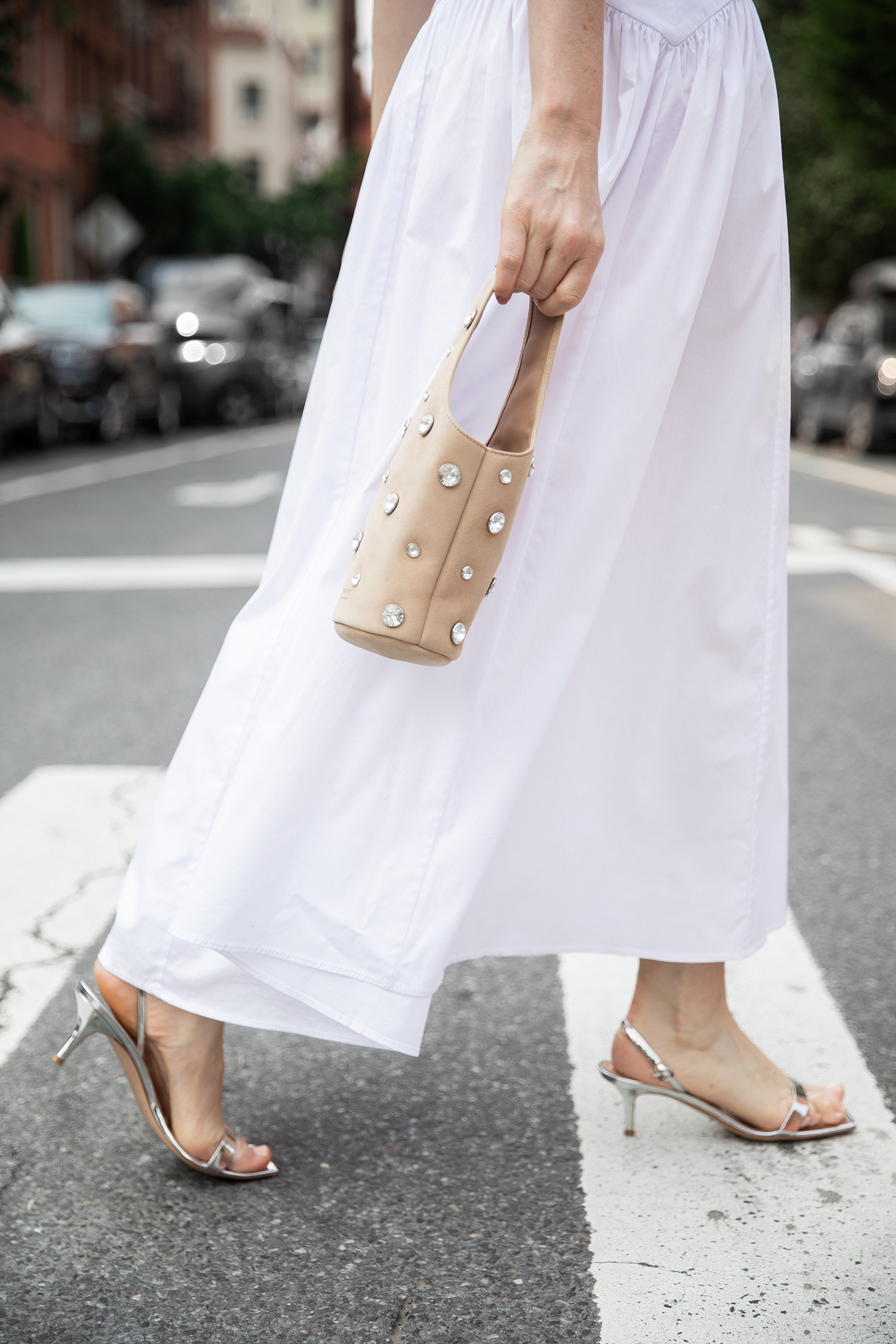 MERRITT BECK IN A STAUD ROMY SLEEVELESS SHIRTDRESS AND A KHAITE LIVIA BAG IN POWDER SUEDE